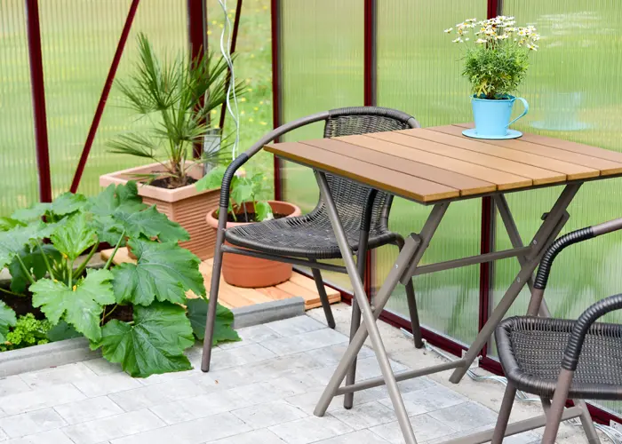 Serre aménagée en espace repas avec table et chaises