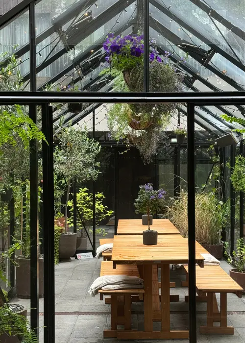 Grande serre de jardin aménagée en salon pour recevoir des amis